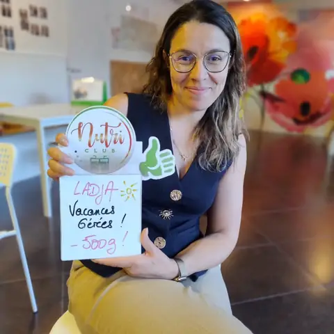 Ardoise levée et grand sourire, une membre montre son bilan